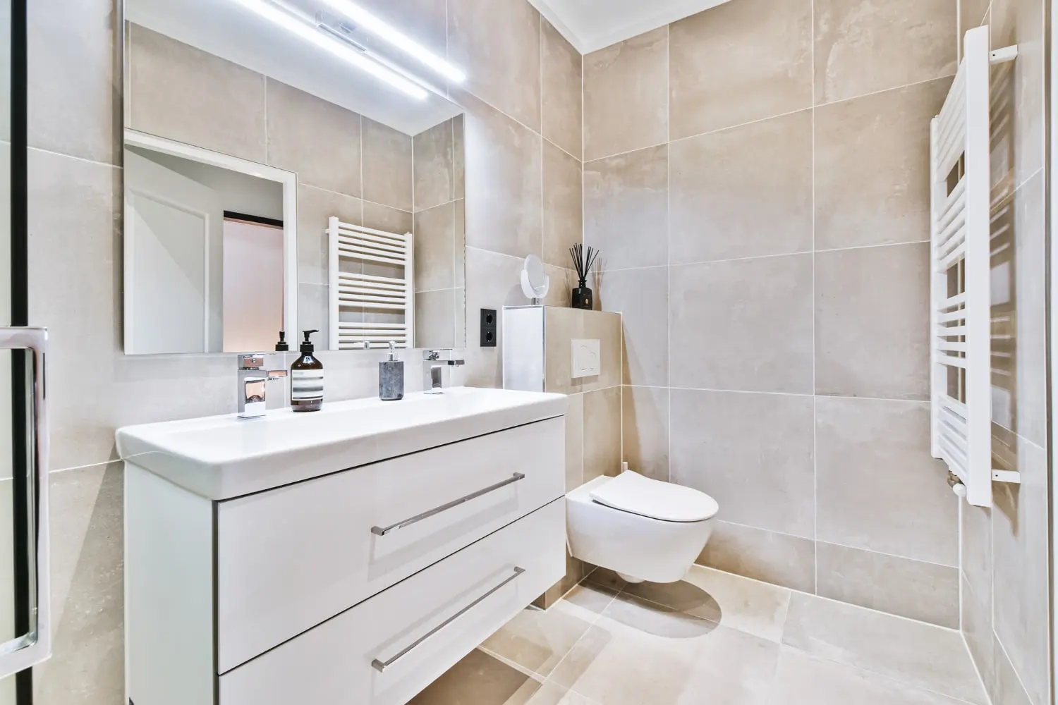 Completed beige bathroom remodel with vanity and towel radiator